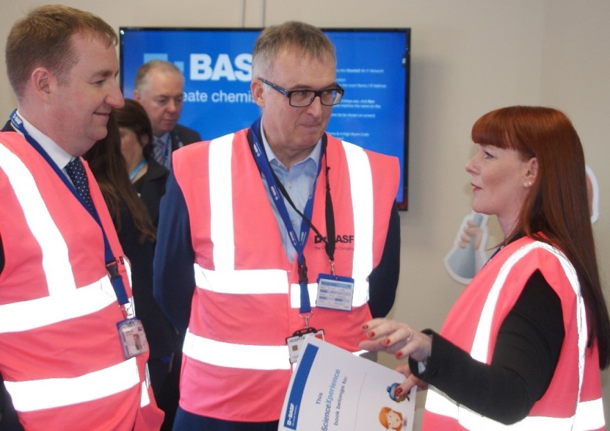 Colleagues in pink hi-vis jackets having a discussion.