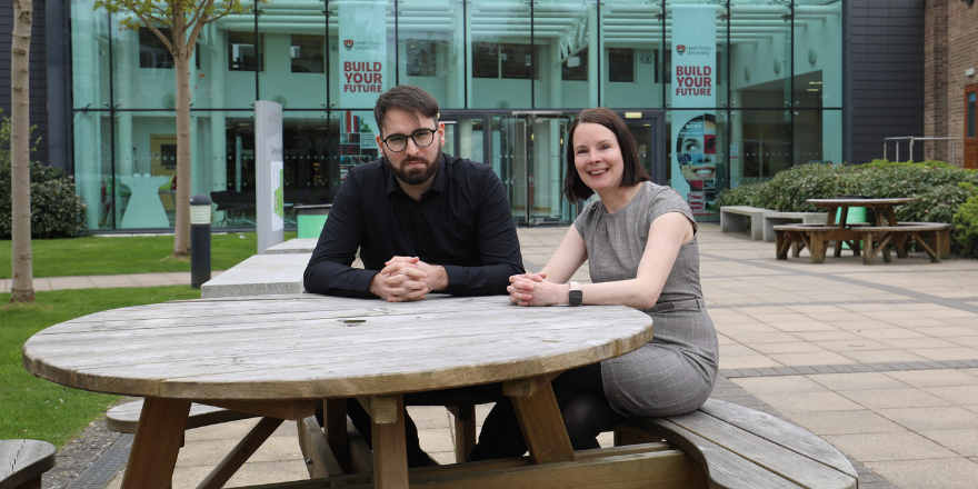 Man and women sat at table outside university building