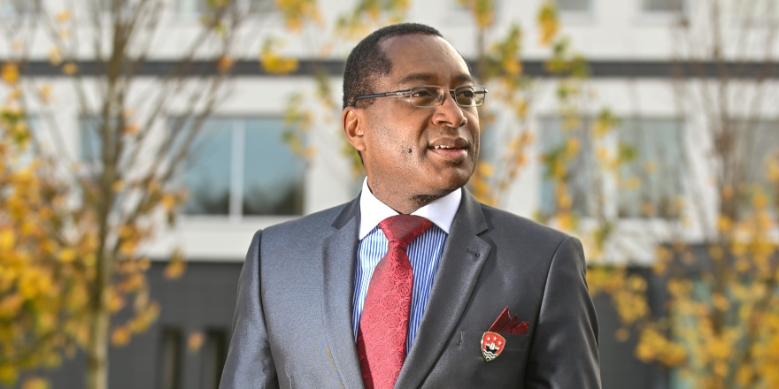 Man in glasses with grey suit jacket, blue shirt and red tie