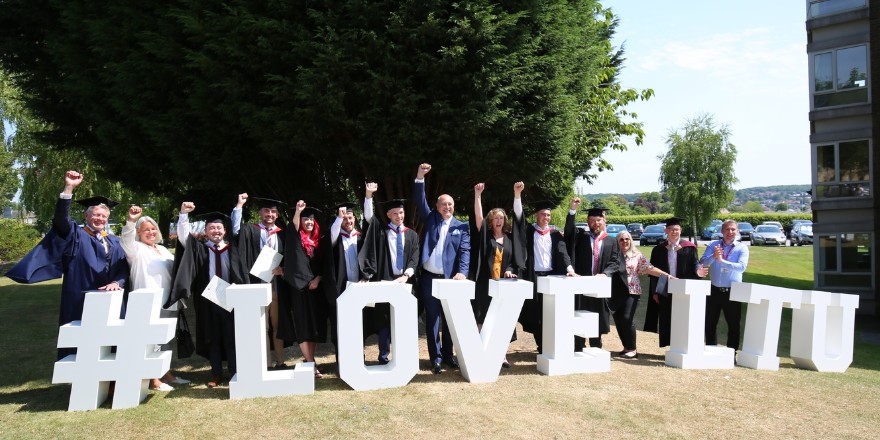 Graduates and lecturers stood by lettering in university grounds