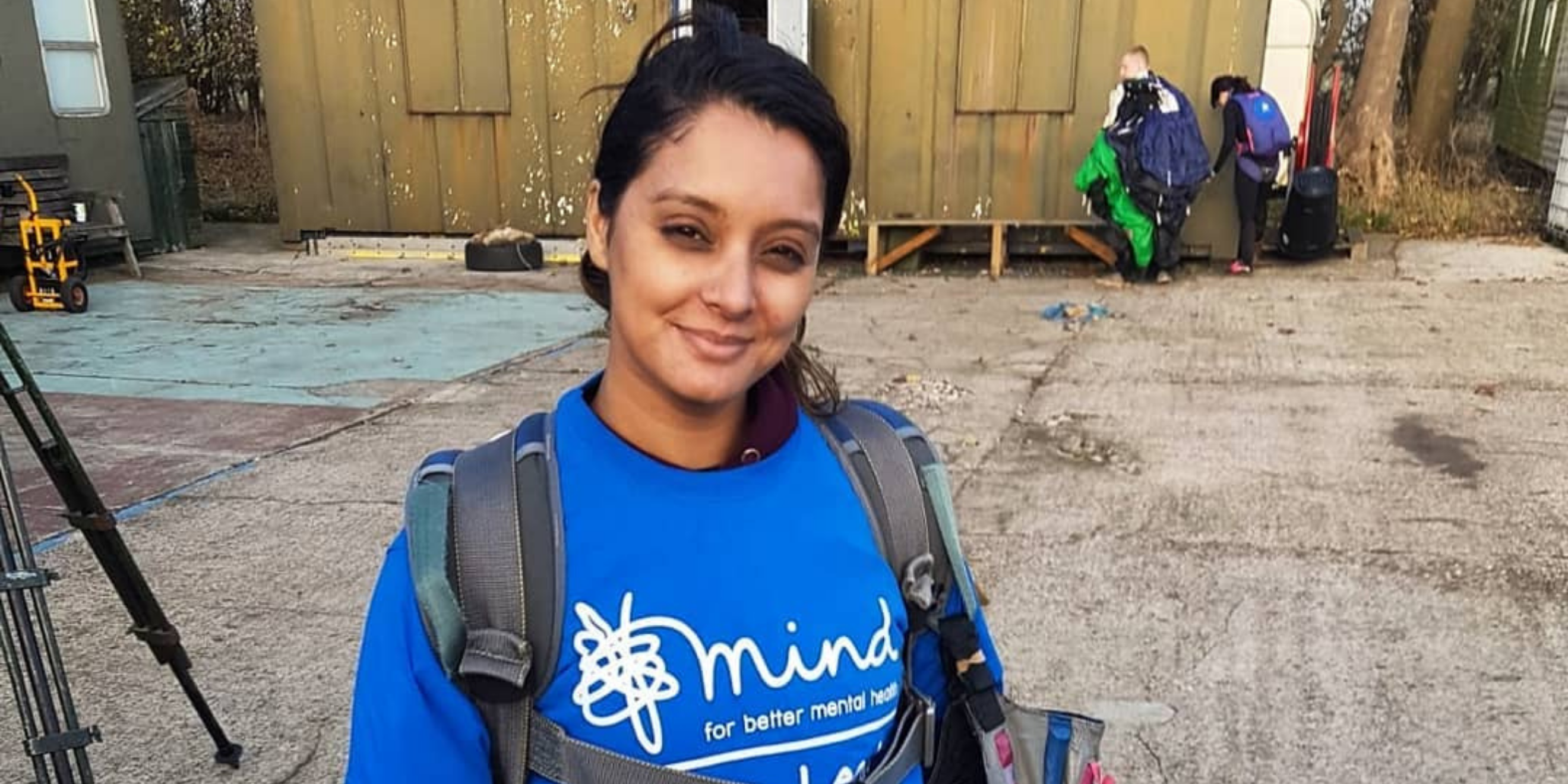 Woman with dark hair and backpack over her shoulders with blue Mind t-shirt on