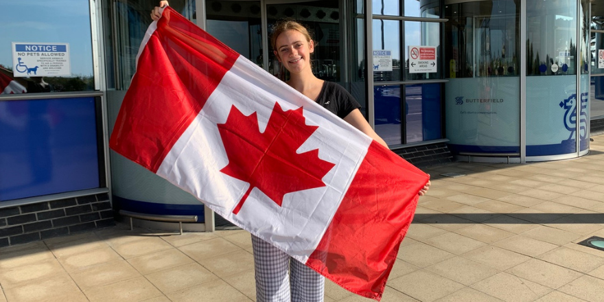 Student holds up Canadian flag at airport departure
