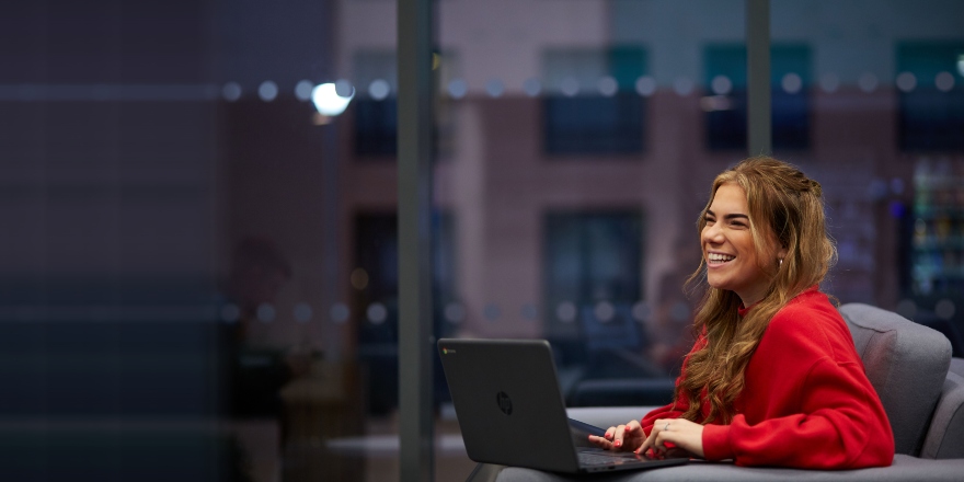 Female student in red jumper with laptop