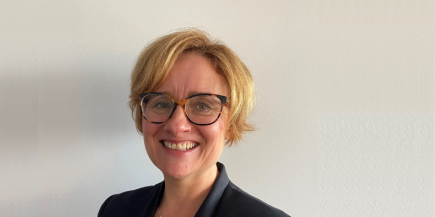 blonde woman with glasses and black suit jacket